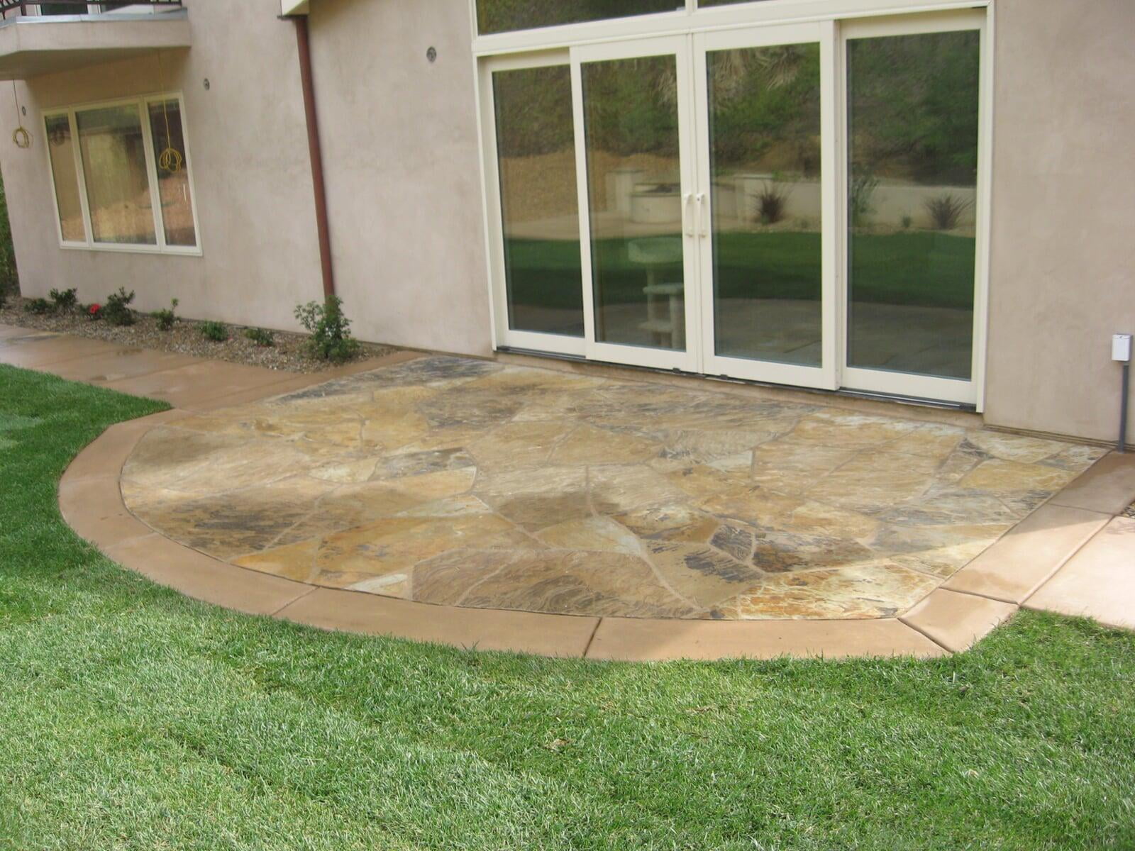 Natural-stone rear patio replacing a yard that pooled water against the house